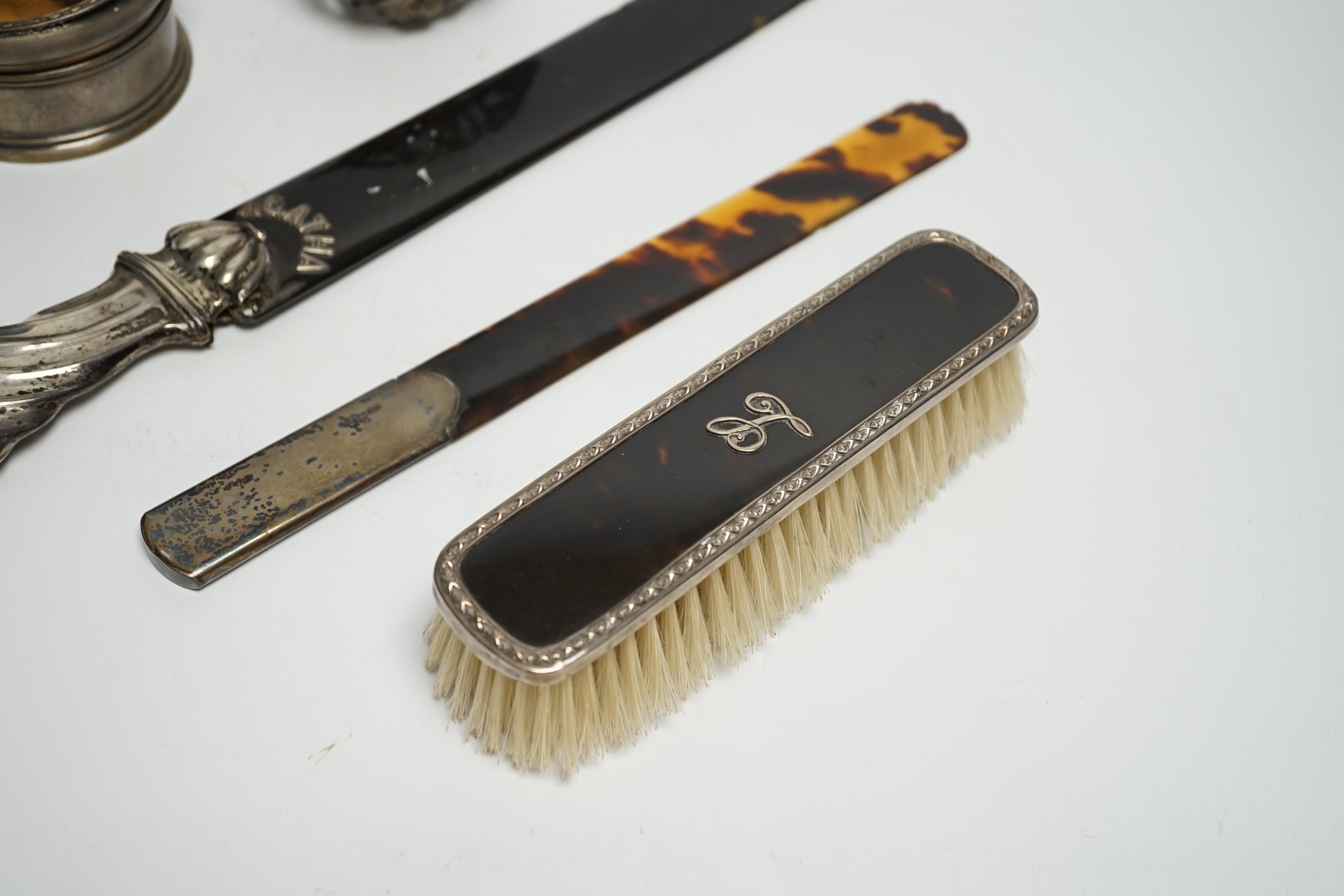 A late Victorian silver handled tortoiseshell page turner, a small page turner, a silver and tortoiseshell box and brush and a white metal pomander case.